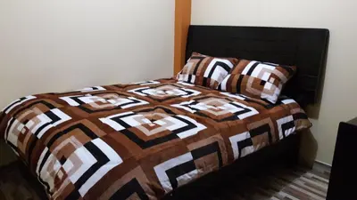 a bed with a brown and white comforter and pillows at Hospedaje Samarina in Acobamba