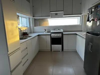 a kitchen with white cabinets and a stove and a window at Tanaka Beach House in Tanaca