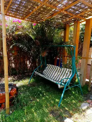 a bench sitting under a pergola in the grass at Bugambilia house in La Tinguiña