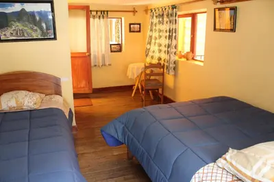 a bedroom with two beds and a table and chairs at Las Portadas in Ollantaytambo