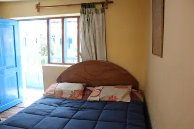 a bedroom with a bed with a wooden headboard and a window at Las Portadas in Ollantaytambo