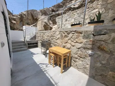 a wooden table in front of a stone wall at Little Oasis in Lima penthouse with pool, Grill, nice view, gated community in Ciudad de Dios
