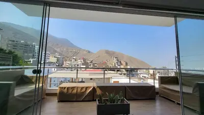 a balcony with a table and a view of a city at Little Oasis in Lima penthouse with pool, Grill, nice view, gated community in Ciudad de Dios