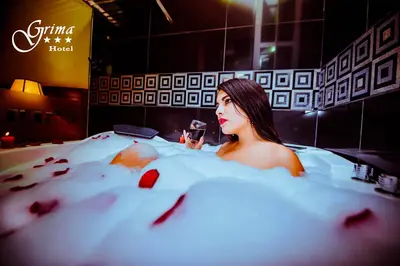 a woman sitting in a bath tub with a glass of wine at Grima Hotel in Huánuco
