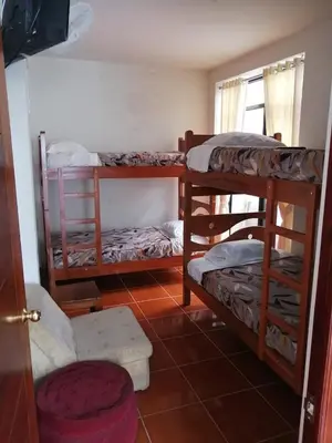 a room with three bunk beds and a chair at Casa Hospedaje Las Lomas con piscina en La Merced in La Merced