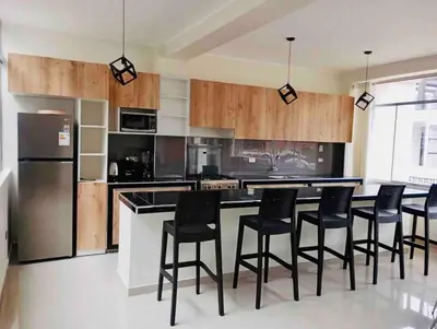 a kitchen with a bar with chairs and a refrigerator at Exclusivo Depa Cerca Precio Uno para 10 in La Merced
