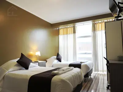 a hotel room with three beds and a window at EmbajadaWanka in Huancayo