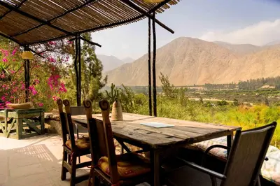 a wooden table and chairs with a view of mountains at Las Cabañas de Tarii in Cieneguilla