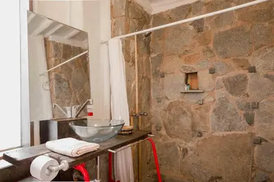 a bathroom with a stone wall and a sink at Las Cabañas de Tarii in Cieneguilla