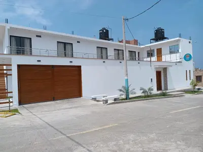 a large white building with a brown garage at Hotel Costa Arena in Supe
