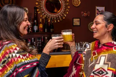 two women drinking beer at a bar at Union Hotel Cusco in Cusco