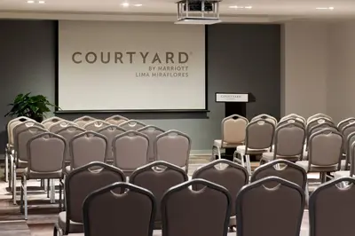 a conference room with chairs in front of a screen at Courtyard by Marriott Lima Miraflores in Lima