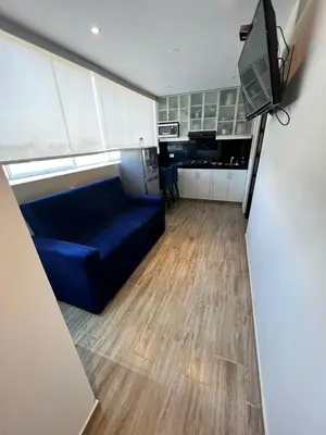 a living room with a blue couch and a kitchen at Miraflores Mini Apartment in Lima