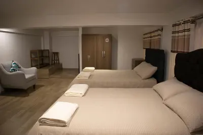 a hotel room with two beds and a chair at La Almudena hogar tranquilo y acogedor in Cusco