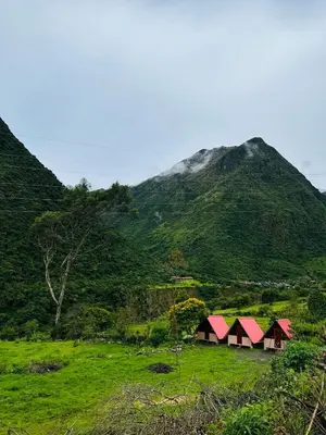 a group of houses in a field with a mountain at Salkantay Glamp in Colcapampa
