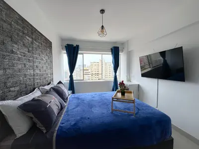 a bedroom with a blue bed and a tv at Miraflores 1 habitación in Lima