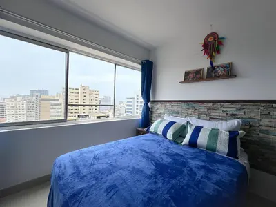 a bedroom with a blue bed and a large window at Miraflores 1 habitación in Lima