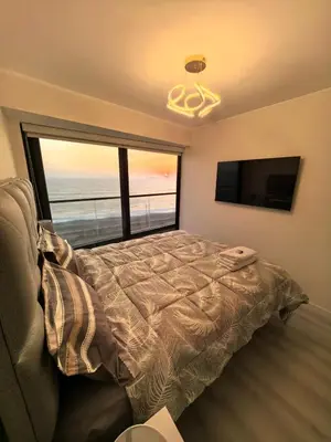 a bedroom with a bed and a large window at Elegante Departamento vista al mar en Lima in Lima