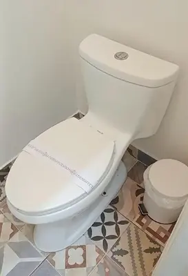 a white toilet in a bathroom with a tile floor at Colville Hospedaje, a 1 cuadra de la plaza mayor de lima in Lima