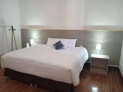 a bedroom with a large white bed with two lamps at Colville Hospedaje, a 1 cuadra de la plaza mayor de lima in Lima