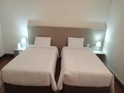 two beds in a hotel room with white sheets at Colville Hospedaje, a 1 cuadra de la plaza mayor de lima in Lima