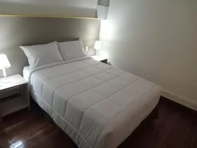 a large white bed in a bedroom with two tables at Colville Hospedaje, a 1 cuadra de la plaza mayor de lima in Lima