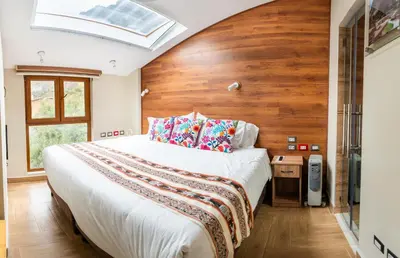 a bedroom with a large bed with a wooden wall at Hotel Boutique PLAZA GIBAJA in Ollantaytambo