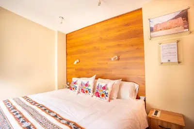 a bedroom with a white bed with a wooden headboard at Hotel Boutique PLAZA GIBAJA in Ollantaytambo