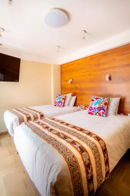 two beds in a hotel room with wooden walls at Hotel Boutique PLAZA GIBAJA in Ollantaytambo