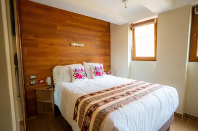 a bedroom with a large bed with a wooden headboard at Hotel Boutique PLAZA GIBAJA in Ollantaytambo
