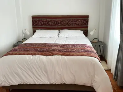 a bedroom with a large bed with a red and white blanket at La Maison Samaï in Urubamba