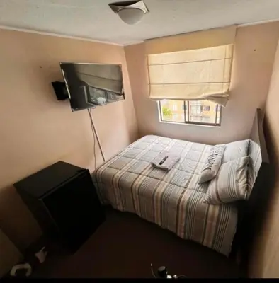 a small bedroom with a bed and a television at Katari Home Peru in Lima