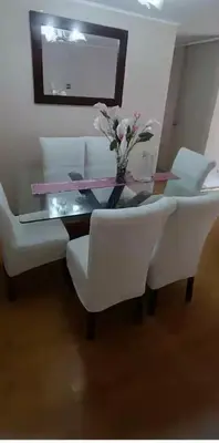 a dining room table with white chairs and a vase of flowers at Katari Home Peru in Lima