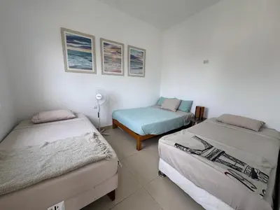 a room with two beds and a table with a fan at Casa Chocaya Playa Campo in Fundo Copacabana
