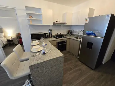 a small kitchen with a counter and a refrigerator at Acogedor Departamento en Cusco, Ideal para Familias y Amigos, Equipado y Céntrico in Cusco