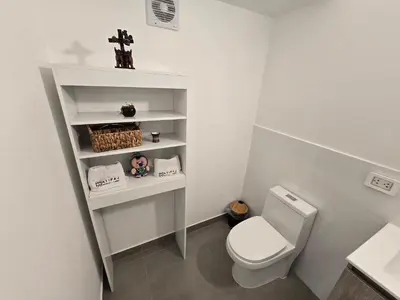 a white bathroom with a toilet and a shelf at Acogedor Departamento en Cusco, Ideal para Familias y Amigos, Equipado y Céntrico in Cusco