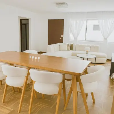 a living room with a wooden table and white chairs at Bello departamento frente a Larcomar Miraflores in Lima