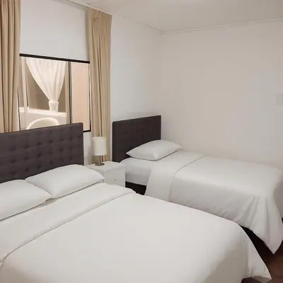 two beds in a hotel room with white sheets at Bello departamento frente a Larcomar Miraflores in Lima