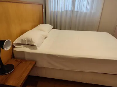 a bed with white sheets and pillows in a room at Apartamento Limas Airport in Lima