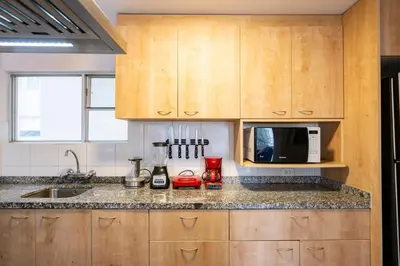 a kitchen with wooden cabinets and a microwave at Reducto - Beautiful 3 BRD Front of Miraflores biggest Park in Lima