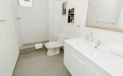 a white bathroom with a toilet and a sink at Romanet - Depa Premium con Vista al Golf in Lima