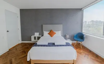 a bedroom with a large bed and a blue chair at Romanet - Depa Premium con Vista al Golf in Lima