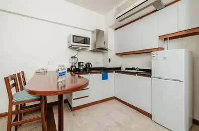 a kitchen with a wooden table and a white refrigerator at Alcanfores - Tu Escapada Urbana Perfecta in Lima