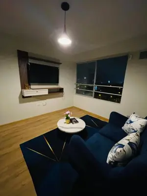a living room with a blue couch and a table at Apartamento moderno en San Miguel in Lima