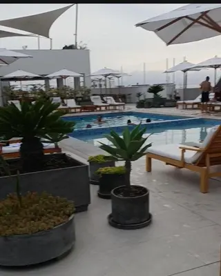 a pool with palm trees and chairs and a swimming pool at Dpto de Playa Miramar San Bartolo in San Bartolo