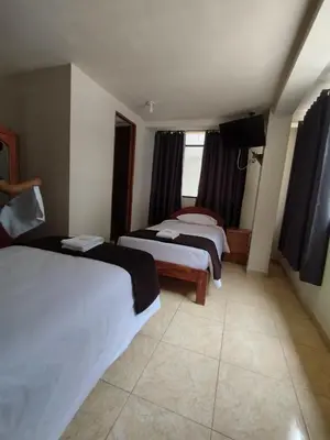 a hotel room with two beds and a flat screen tv at Kuntur House Machupicchu in Machu Picchu