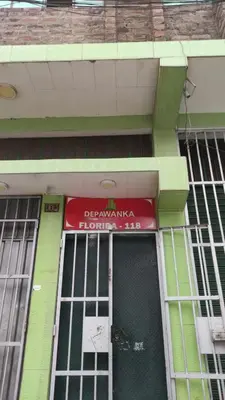 a green building with a red sign above a door at Depawanka habitacion amoblado in Huancayo