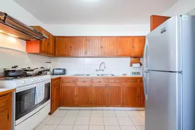 a kitchen with wooden cabinets and a white refrigerator at M701 Malecón View Apartment 3 BDR in Lima