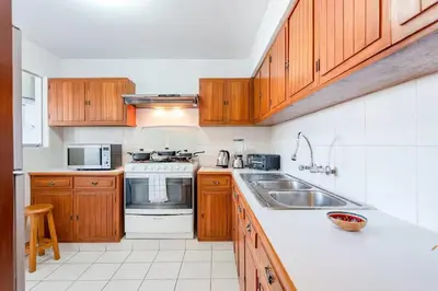 a kitchen with wooden cabinets and a stove and a sink at M701 Malecón View Apartment 3 BDR in Lima