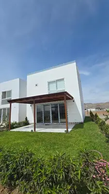 a large white building with a roof on a lawn at Casa de Playa de Estreno in Cerro Azul